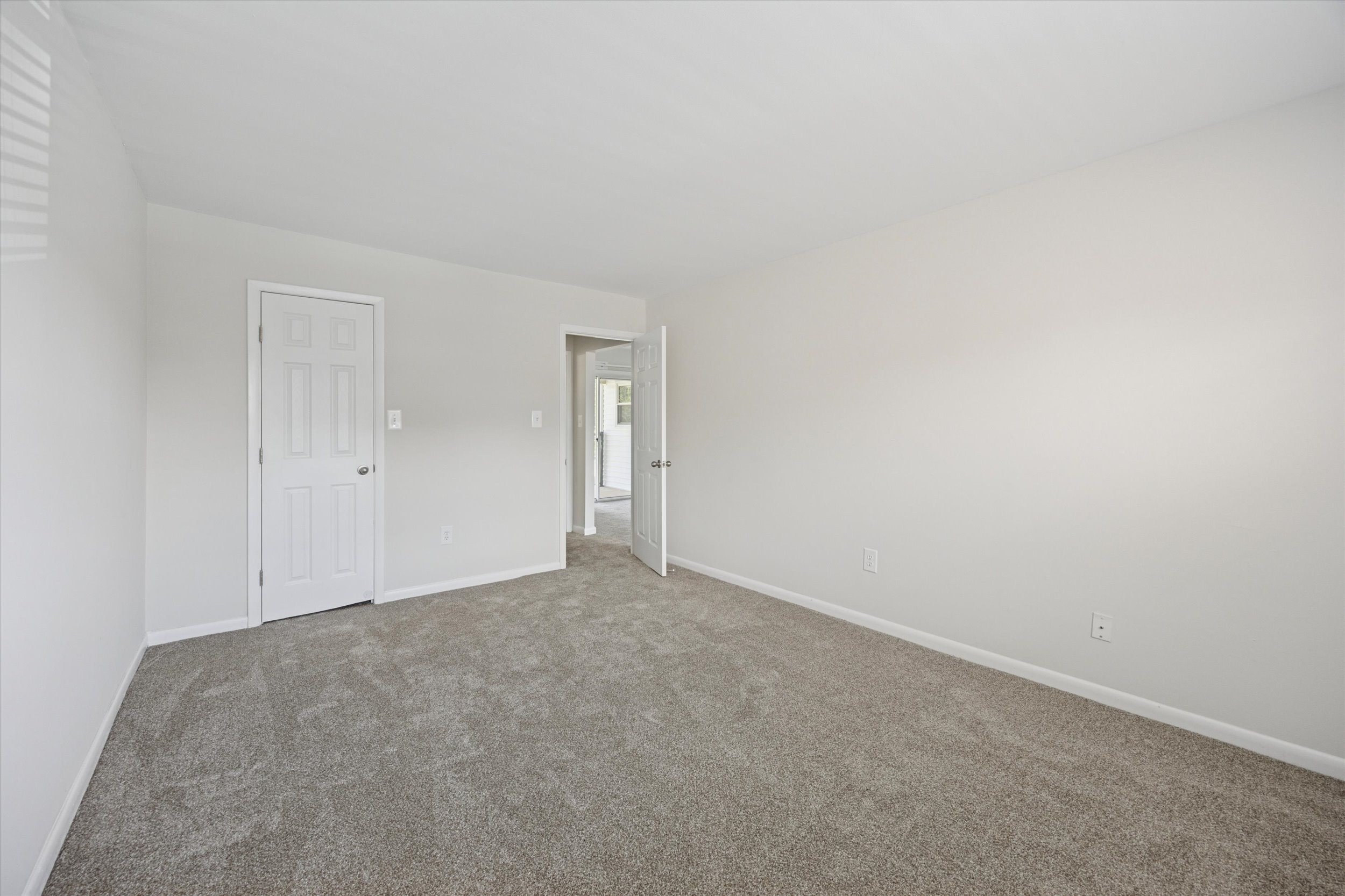 A room with a carpeted floor and two doors.